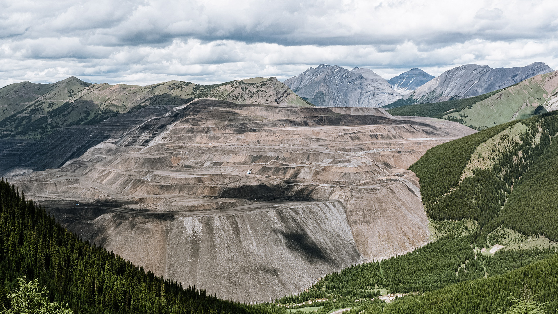 a desolate open pit mine surrounded by trees and mountains